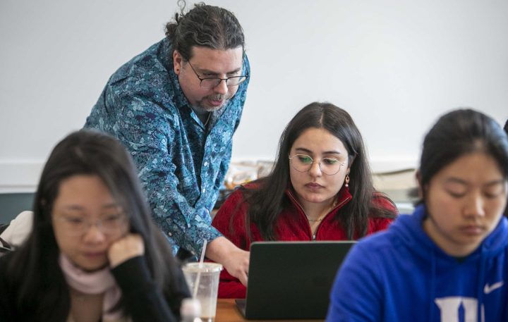 Instructor helping a student with something on their opened laptop.